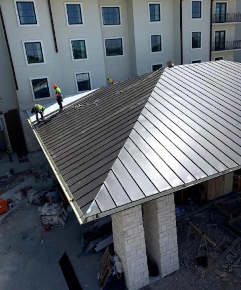 Crew installing standing seam metal roof panels on a commercial project in Green Lake